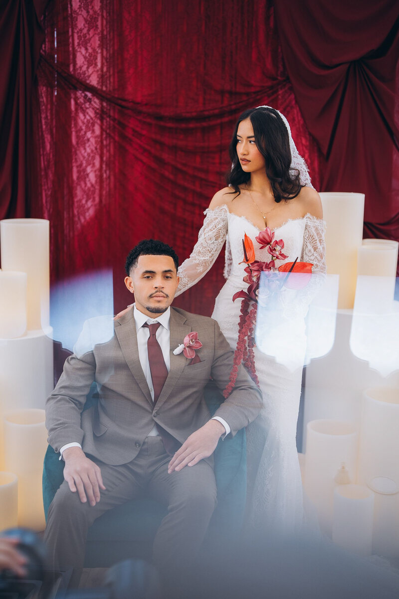 Oversized Candles Illuminated with LED Lights Surrounding Bride and Groom Against Red Velvet Backdrop